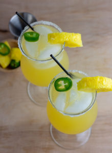 overhead of two sweet hot mama cocktails with ice, pineapple and jalapeño