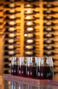 red wine flight in front of wine cellar Checkered Past Winery